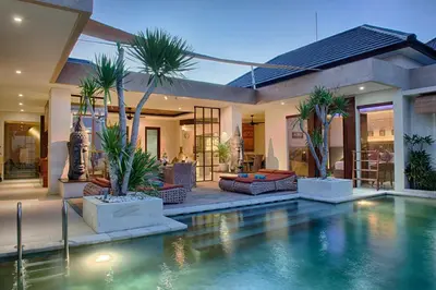 a house with a swimming pool with palm trees in it at Villa Lisha in Canggu