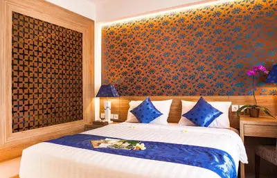 a bedroom with a bed with a blue and orange wall at Natya Hotel Kuta in Kuta