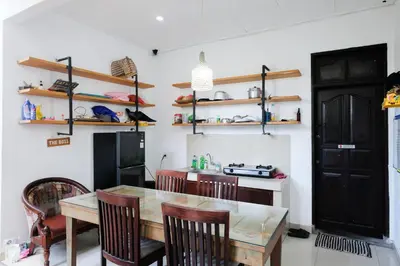 a kitchen with a table and chairs and a refrigerator at RedDoorz at Serenity Inn Teuku Umar Denpasar in Denpasar