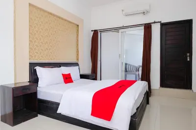 a bedroom with a bed with a red blanket on it at RedDoorz at Serenity Inn Teuku Umar Denpasar in Denpasar