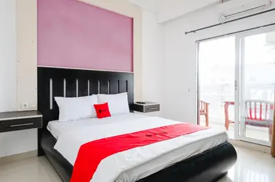 a bedroom with a large bed with a red blanket at RedDoorz at Serenity Inn Teuku Umar Denpasar in Denpasar