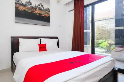 a bedroom with a large bed with a red blanket at RedDoorz at Serenity Inn Teuku Umar Denpasar in Denpasar