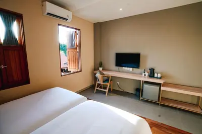 a bedroom with a bed and a desk with a television at Tanaga CoLiving in Seminyak