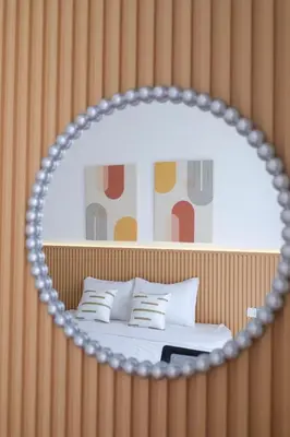 a mirror reflecting a bedroom with a bed with white pillows at Olivia SOHO Guest House in Legian