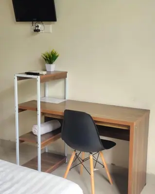 a desk with a chair in a room with a television at Olivia SOHO Guest House in Legian