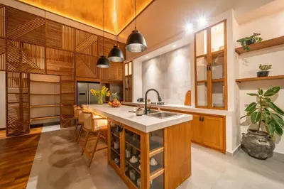 a kitchen with a island with a sink and wooden cabinets at Villa Mango 2 - Amazing 4-bdr Villa in Berawa ! PERFECT LOCATION in Canggu
