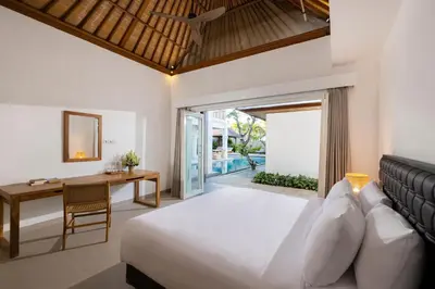 a bedroom with a bed and a table and a desk at Villa Christie By Nakula in Seminyak