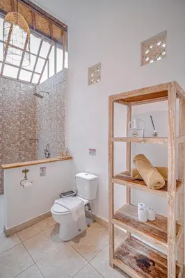 a bathroom with a toilet and a wooden shelf at Villa Deba 3 by Bali Villa Solutions in Seminyak