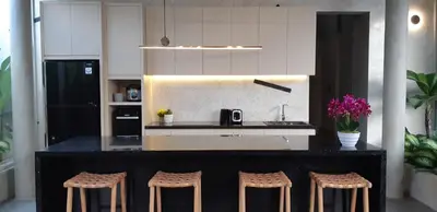 a kitchen with a black counter and stools at Villa Mandja - Stunning architect-designed 3BR villa in Petitenget in Seminyak