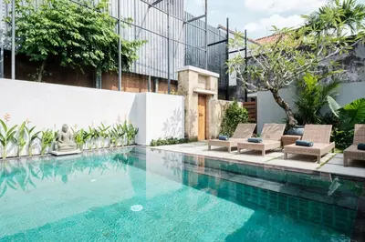 a swimming pool with chairs and a building at Kundalini Residence in Seminyak
