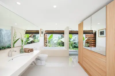a bathroom with a toilet and a sink and windows at Kundalini Residence in Seminyak