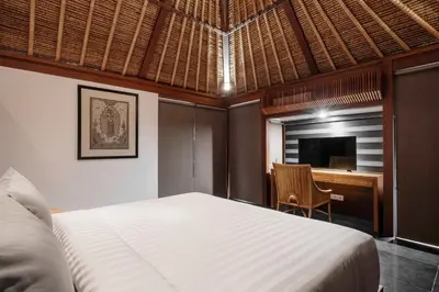 a bedroom with a bed and a desk and a television at Kundalini Residence in Seminyak
