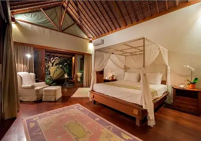 a bedroom with a canopy bed and a chair at Villa Andalas in Seminyak