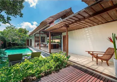 a patio with a table and chairs and a swimming pool at Villa Andalas in Seminyak