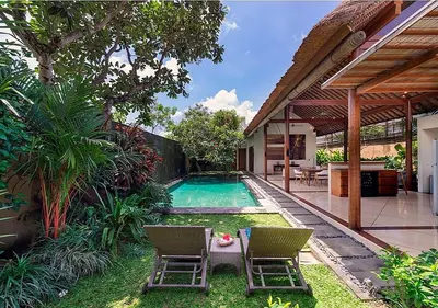a backyard with a swimming pool and two chairs at Villa Andalas in Seminyak
