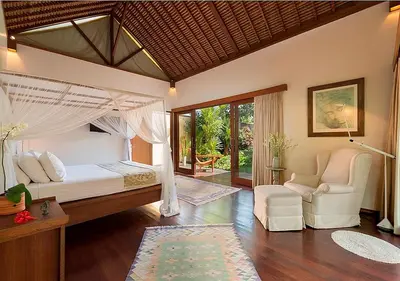 a bedroom with a bed and a couch and a chair at Villa Andalas in Seminyak
