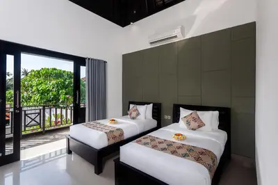 two beds in a room with a balcony at Maja Villa Batubelig by GenuineHost in Canggu