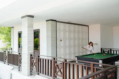 a woman playing pool on the balcony of a house at Maja Villa Batubelig by GenuineHost in Canggu