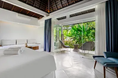 a bedroom with a white bed and a large window at Umani Village in Kerobokan
