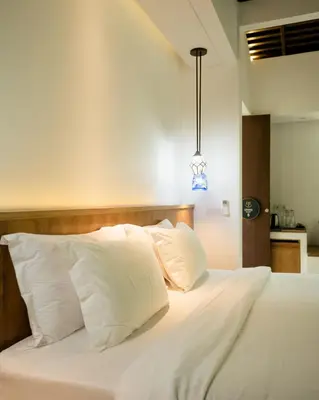 a bedroom with a bed with white sheets and pillows at Umani Village in Kerobokan