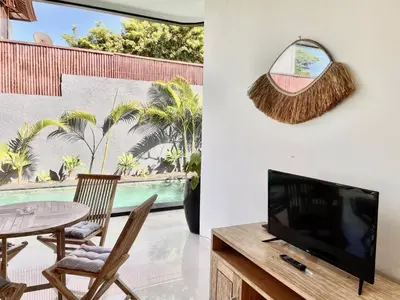 a living room with a television and a table and chairs at VILLA LUNA in Kerobokan
