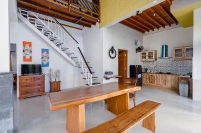 a kitchen with a wooden table and a staircase at Villa Padma by Best Deals Asia Hospitality in Nusa Dua