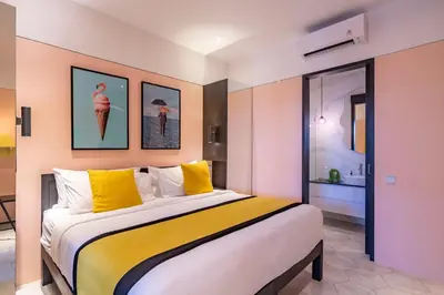 a bedroom with a large bed with yellow pillows at Villa Caorrun Canggu in Canggu