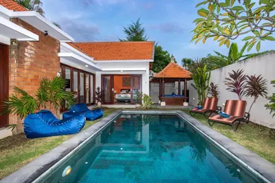 a swimming pool in front of a house at Villa Kamboja Premium walk to double six Beach - enclosed living room with AC in Seminyak