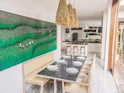 a dining room with a green painting on the wall at AB Villa & Apartments in Seminyak
