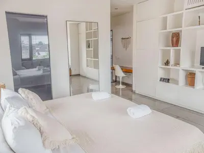 a white bedroom with a large bed and a bathroom at AB Villa & Apartments in Seminyak