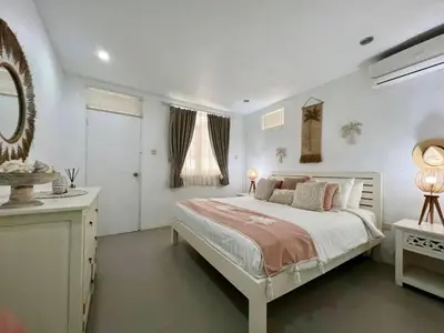 a white bedroom with a large bed and a mirror at Tiga Pantai Villa Legian in Legian