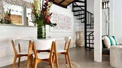 a dining room with a table with chairs and a vase of flowers at Tiga Pantai Villa Legian in Legian