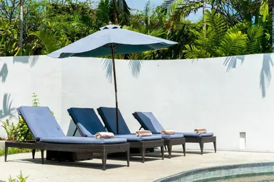 a group of chairs and an umbrella next to a pool at Villa Damai Kecil Seminyak by Adam Jyota Management in Seminyak