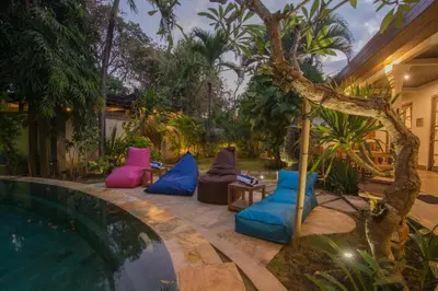 a backyard with a pool with chairs and a tree at Bale Seminyak in Seminyak