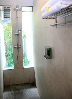 a shower stall in a bathroom with a window at Delu Villas & Suite in Kerobokan