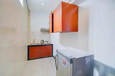 a small kitchen with a sink and a refrigerator at Collection O Bali near Kedonganan Beach formerly New Asta Graha Homestay in Jimbaran