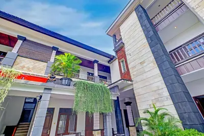 a house with a palm tree in front of it at Collection O Bali near Kedonganan Beach formerly New Asta Graha Homestay in Jimbaran