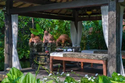 a bench under a pavilion with a table and sculptures at Villa Kapungkur in Jimbaran