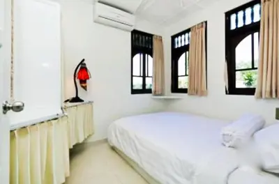 a white bedroom with a bed and two windows at Blue Lagoon Apartment 3br in Kuta