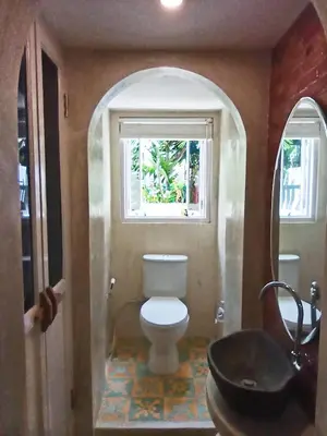 a bathroom with a toilet and a window and a sink at Beach House Apartment in Legian