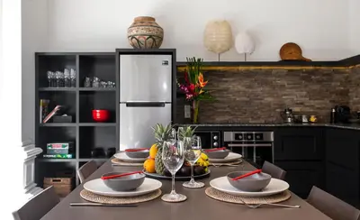 a kitchen with a table with plates and wine glasses at Villa Rua - Stylish luxury, tranquil location in Legian, walk to beach in Seminyak