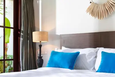a bedroom with a bed with blue pillows and a window at Villa Rua - Stylish luxury, tranquil location in Legian, walk to beach in Seminyak