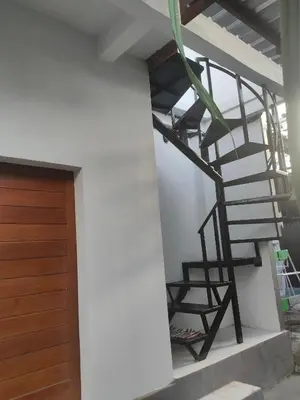 a spiral staircase in a house with a wooden door at Roy Guest House in Canggu