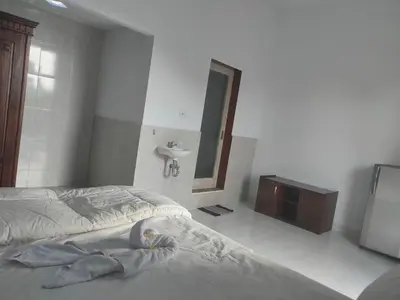 a bedroom with a bed and a sink and a mirror at Roy Guest House in Canggu