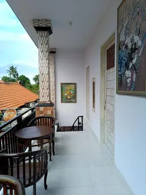 a balcony with tables and chairs on a house at Roy Guest House in Canggu