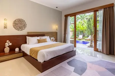 a bedroom with a bed and a large window at Bali Voyage in Seminyak