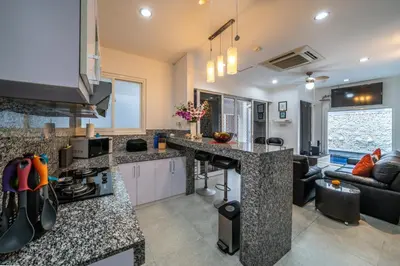 a kitchen with granite counter tops and a living room at Modern villa with private pool , full kitchen and parking in Legian