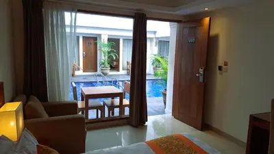 a living room with a couch and a table and a view of a pool at The Sun Hotel & Spa Legian in Legian