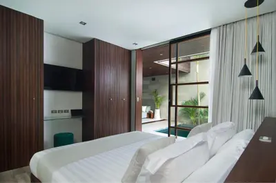 a bedroom with a white bed and a sliding glass door at 4BR Villa Kamis - Minggu Villas Seminyak in Seminyak