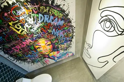 a bathroom with a wall covered in graffiti at 4BR Villa Kamis - Minggu Villas Seminyak in Seminyak